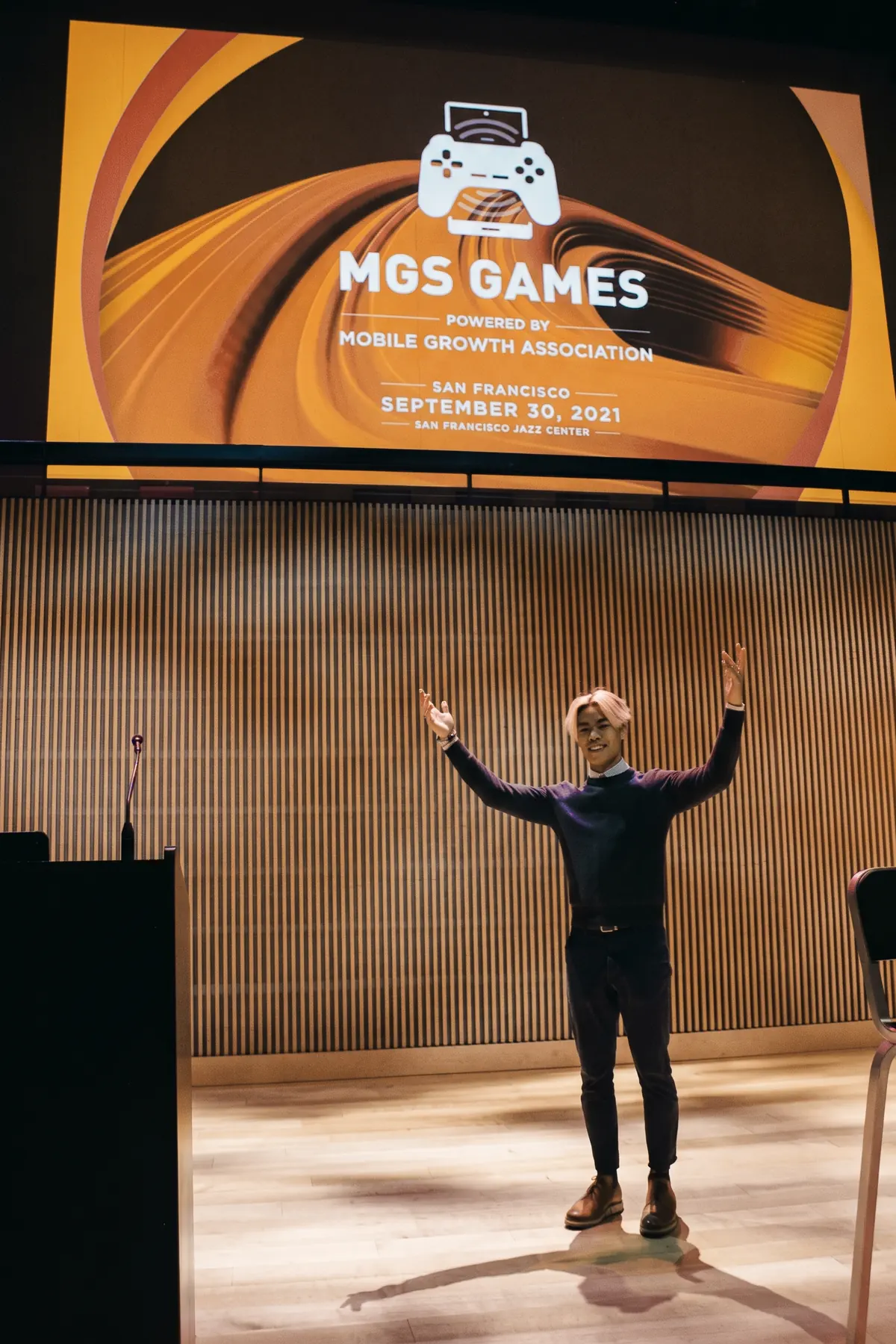 Evan Kwan on stage with arms raised under a screen reading MGS Games, powered by Mobile Growth Association